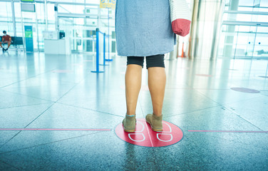 Woman waiting at the airport maintaining social distancing. Social distance to avoid Covid 19.