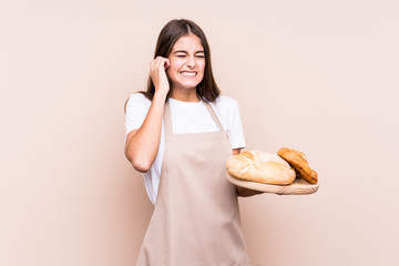 Young caucasian baker woman isolated covering ears with hands.