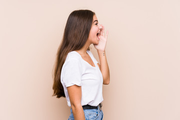 Young caucasian woman posing isolated shouting and holding palm near opened mouth.