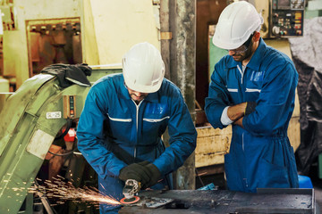 Technician workers work with electric metal grinding disc on steel structure in a factory. Industrial, Warehouse, Heavy Mechanic, Engineering Concept.