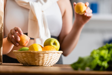 cropped view of woman holding fresh fruits in kitchen