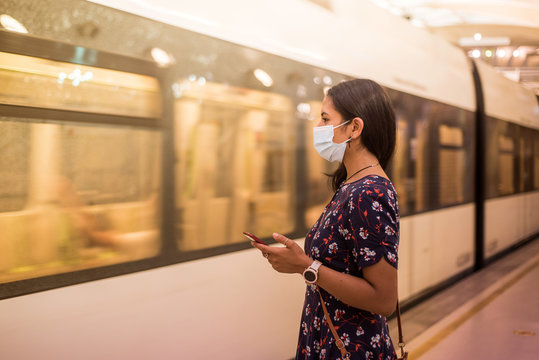 Young woman waits for the subway with a medical mask.