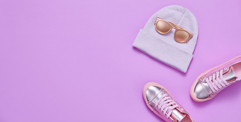 Autumn Fashion. Woman Gold Accessories Set. Minimal Creative Flat lay. Trendy autumnal Beanie Hat, Glamour Shoes, Stylish Sunglasses. Luxury Fall Hipster Girl Outfit on purple color.