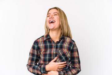 Young blonde caucasian woman isolated laughs happily and has fun keeping hands on stomach.