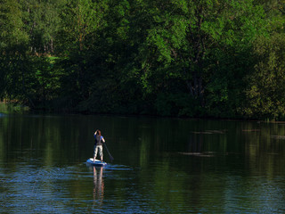 Fototapeta na wymiar Woman sailing on beautiful calm green lagoon. Summer holidays vacation travel. SUP Stand up paddle board
