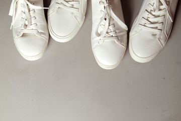 foto horizontal de varios zapatos clasicos de piel blanco puestos en la parte superior dejando un espacio gris abajo