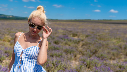 girl on a lilac field smiling at the camera sunglasses standing happy with white skin stands