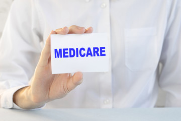 Doctor holding a card with text MEDICARE, medical concept