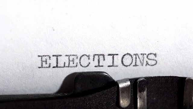 Typing ELECTIONS in black ink on an old vintage typewriter. In the context of US elections in 2020. Close up selective focus
