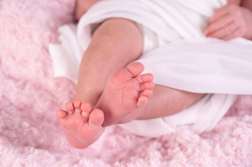 cute newborn baby feet on a white blanket, closeup. selective focus.