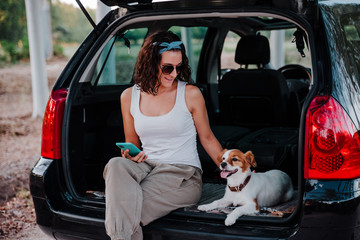 young happy woman in a car enjoying with her cute dog. Travel concept