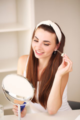 Naklejka premium sitting at home, looking in the mirror, laughing and having fun. Morning skin care regimen.
