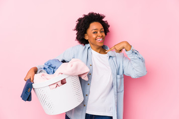 Middle age african american woman doing laundry isolated surprised pointing at himself, smiling broadly.