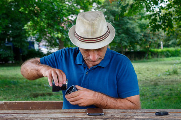 Middle Age Man Watching Instructions on Smart Phone and Trying to Connect Lens With Extension Tubes
