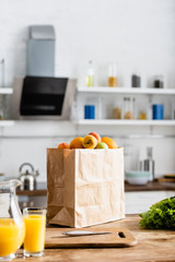 Fototapeta na wymiar selective focus of paper bag with groceries near jug with orange juice