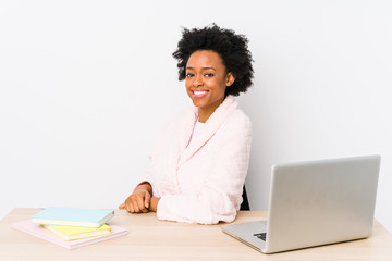 Middle aged african american woman working at home isolated looks aside smiling, cheerful and pleasant.