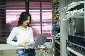 Technician using laptop while analyzing server in data center.