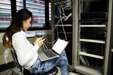 Technician using laptop while analyzing server in data center.