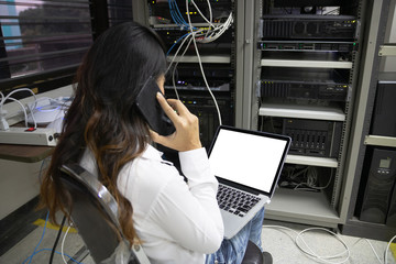 Technician using laptop while analyzing server in data center.