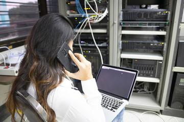 Technician using laptop while analyzing server in data center.