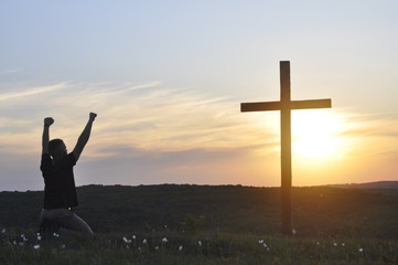 Cross. Young man on his knees. Prayer and worship to God. The cross of Jesus against the sky....