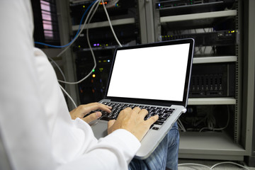 Technician using laptop while analyzing server in data center.