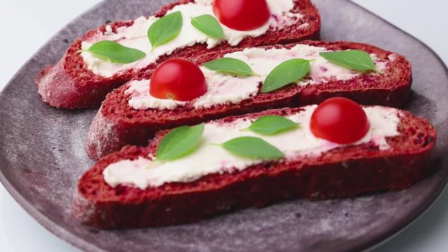 Rotating of red beet bread sandwiches with cream cheese and tomatoes. Side view, close up.