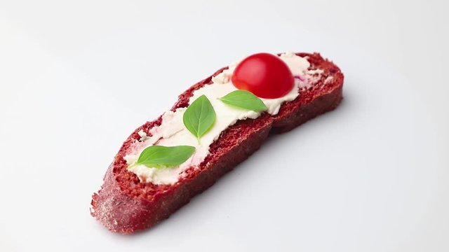 Rotating of red beet bread sandwiches with cream cheese and tomatoes. Side view, close up.
