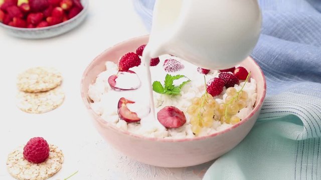 Rice flakes porridge poured with milk in ceramic bowl on white concrete background. Side view, close up.