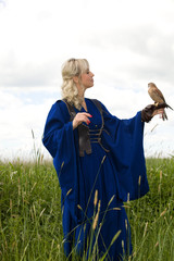 beautiful girl in a long blue medieval dress with a hunting Falcon on her glove