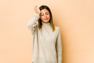 Young woman isolated on beige background tired and very sleepy keeping hand on head.