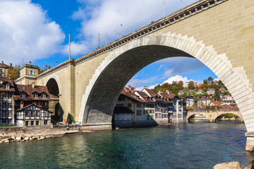 Naklejka premium Beautiful view of Bern old town and Aare river under the Nydeggbrücke bridge with Untertorbrücke bridge, on sunny autumn day with blue sky and cloud, Switzerland