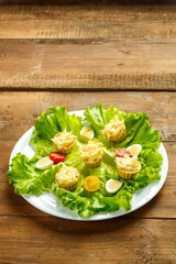 Tartlets with cheese and garlic on a plate with quail eggs salad on a wooden table.