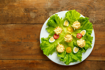 Tartlets with cheese and garlic on a plate with salad on a wooden table.