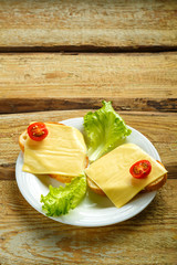 Sandwiches with cheese and cherry on a plate on a wooden table. Copy the place.