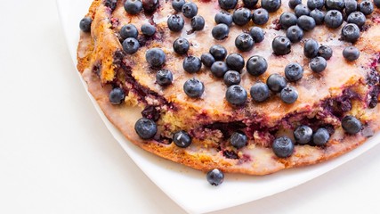A large homemade pie with black currants (not all berries are specially focused) in natural light, on a white plate
