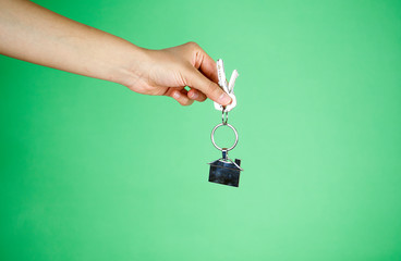 House key in woman hand. green background