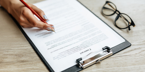 Young girl office worker or business lady signs documents. Concentrated businesswoman working with papers. Business concept