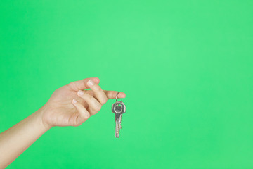 House key in woman hand. green background