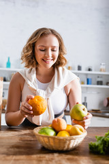 selective focus of woman holding orange and apple in hands