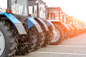 Many different tractors standing in row at agricultural fair for sale outdoors.Equipment for...