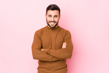 Young caucasian man against a pink background isolated who feels confident, crossing arms with determination.