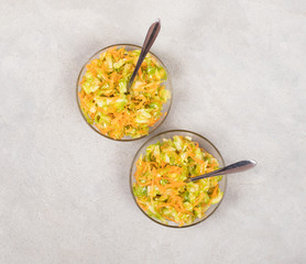 Vegetable salad with cabbage and carrots in a bowl on a light background top view