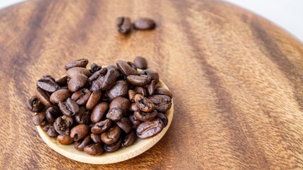 Composition in natural daylight. Coffee beans in a small wooden plate, on a dark wood background