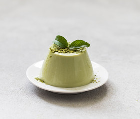 Italian dessert Panna cotta with green matcha tea on a light gray background