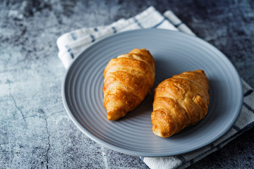 Fresh croissants on a plate with cups of coffee