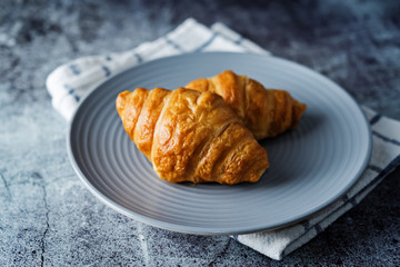 Fresh croissants on a plate with cups of coffee
