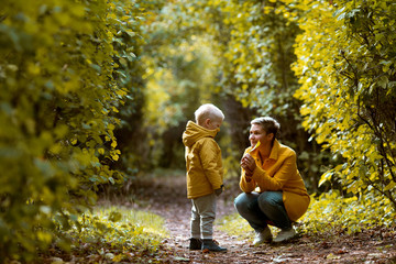 Young woman hugging her small son in the autumn park