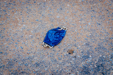 isolated blue homemade protective mask thrown on the street