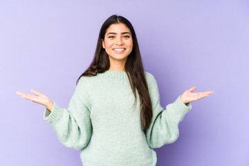 Young indian woman isolated on purple background showing a welcome expression.